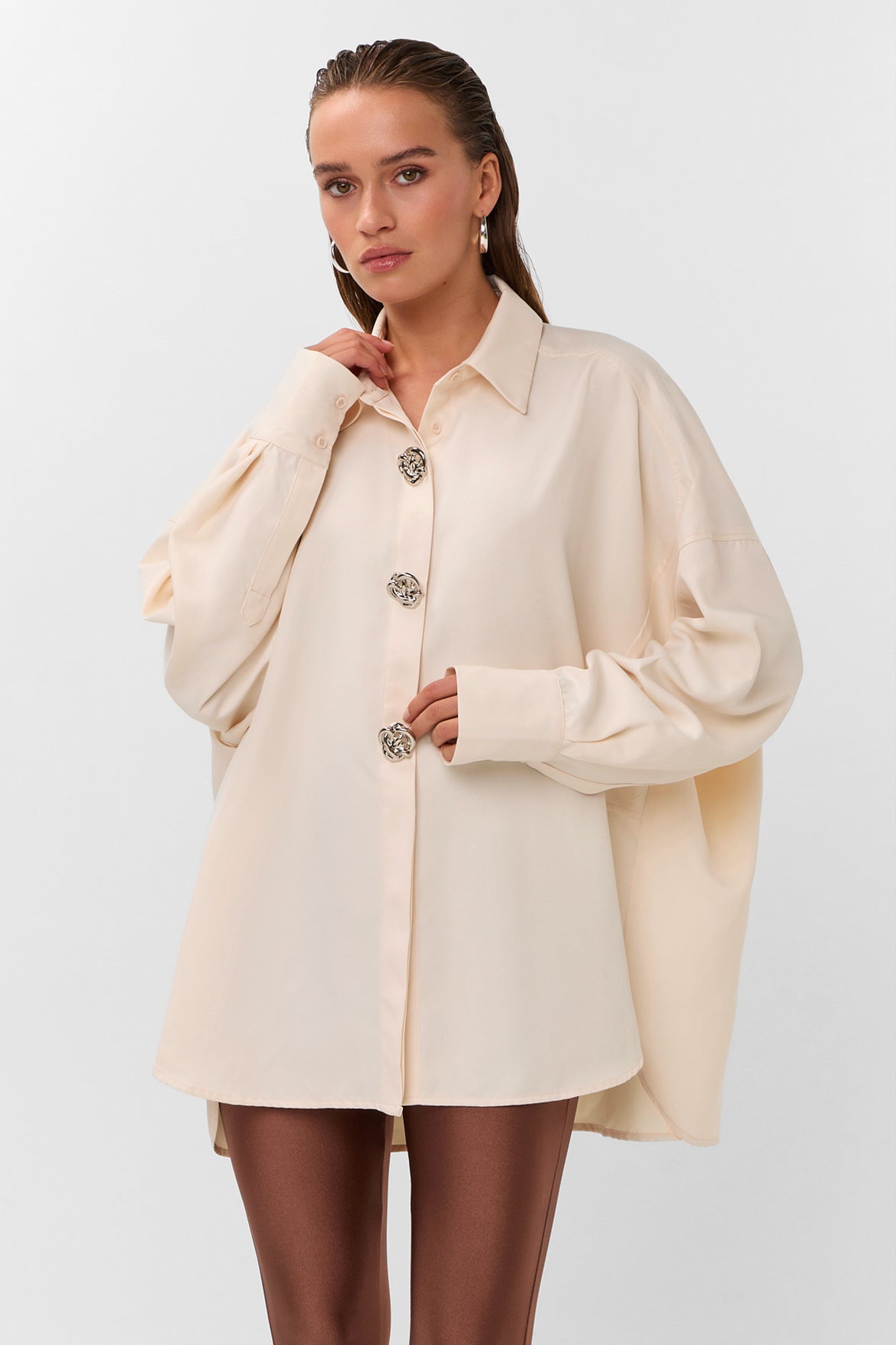 Oversized blouse in warm wit met volumineuze mouwen en opvallende zilverkleurige sierknopen.