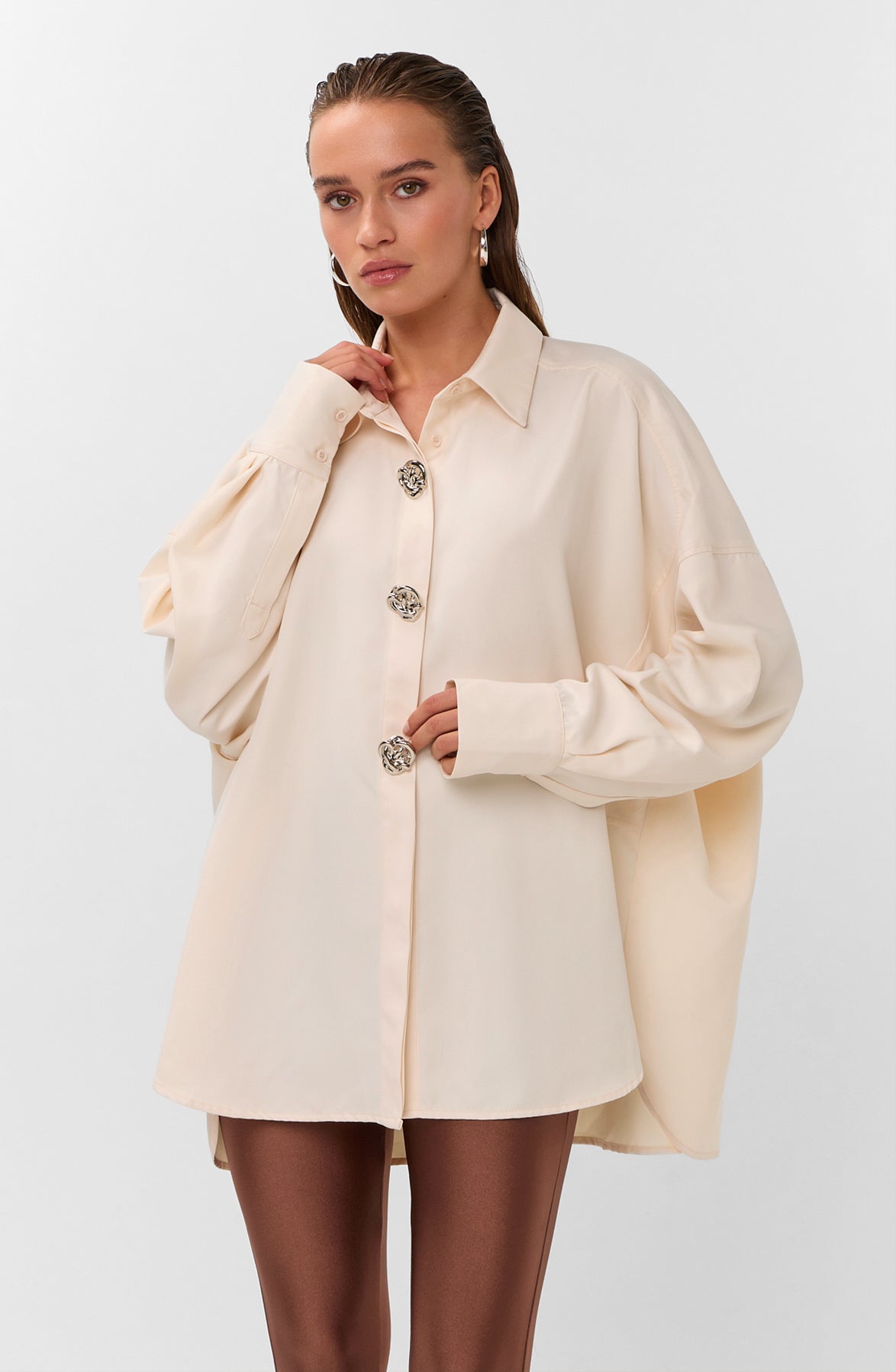 Oversized blouse in warm wit met volumineuze mouwen en opvallende zilverkleurige sierknopen.