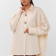 Oversized blouse in warm wit met volumineuze mouwen en opvallende zilverkleurige sierknopen.