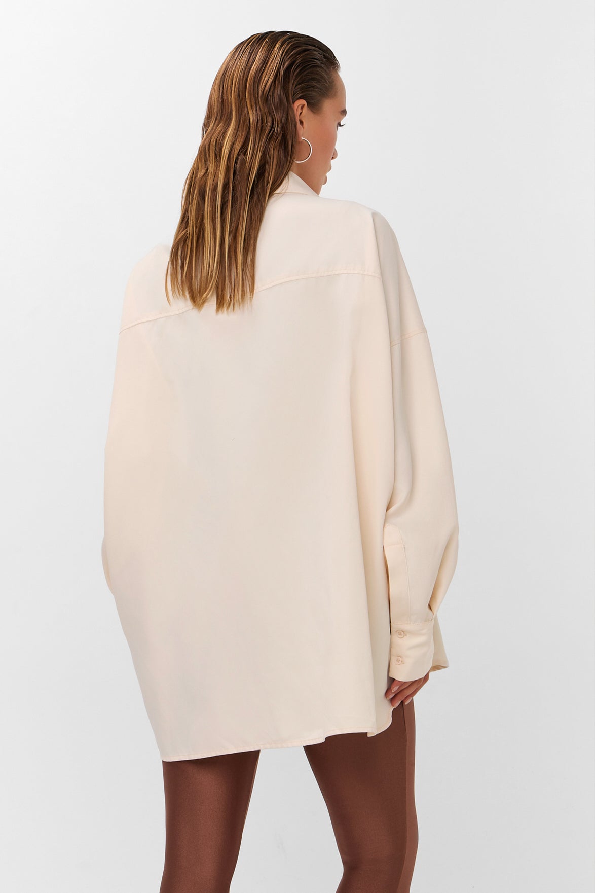 Oversized blouse in warm wit met volumineuze mouwen en opvallende zilverkleurige sierknopen.