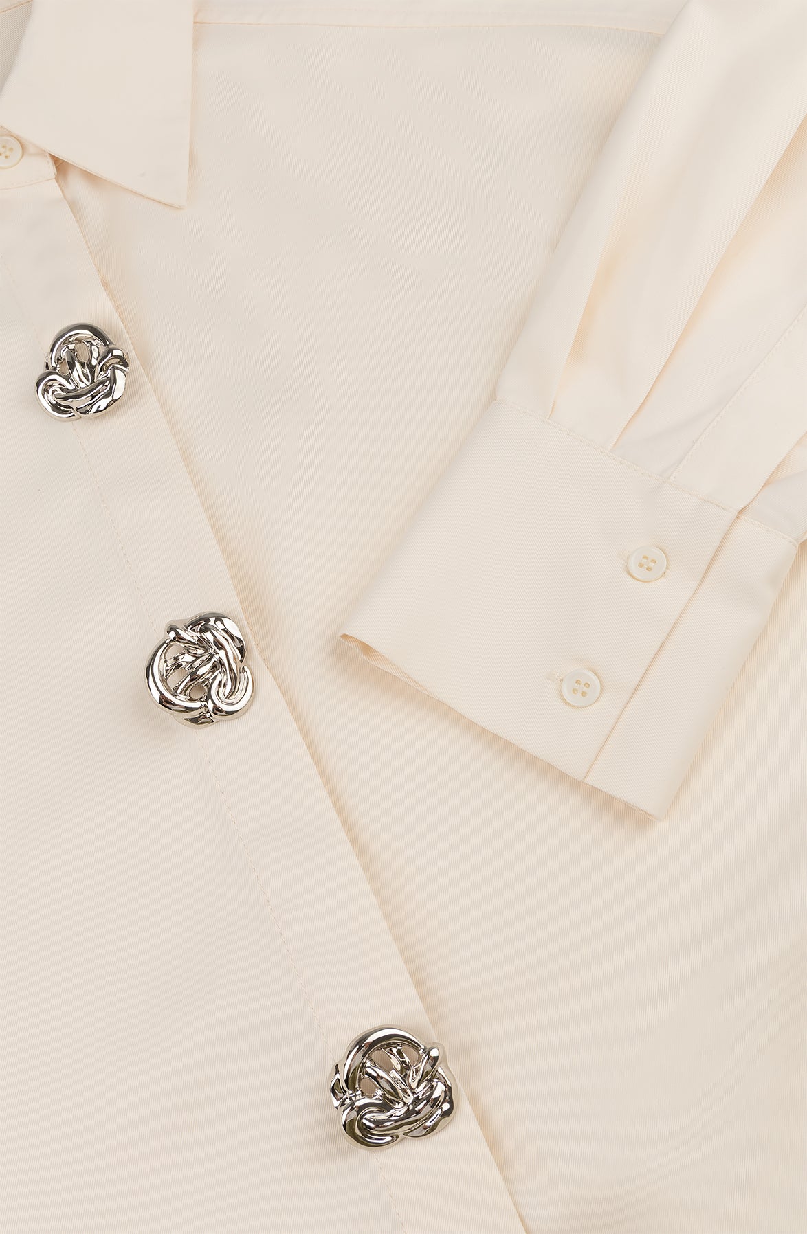 Oversized blouse in warm wit met volumineuze mouwen en opvallende zilverkleurige sierknopen.